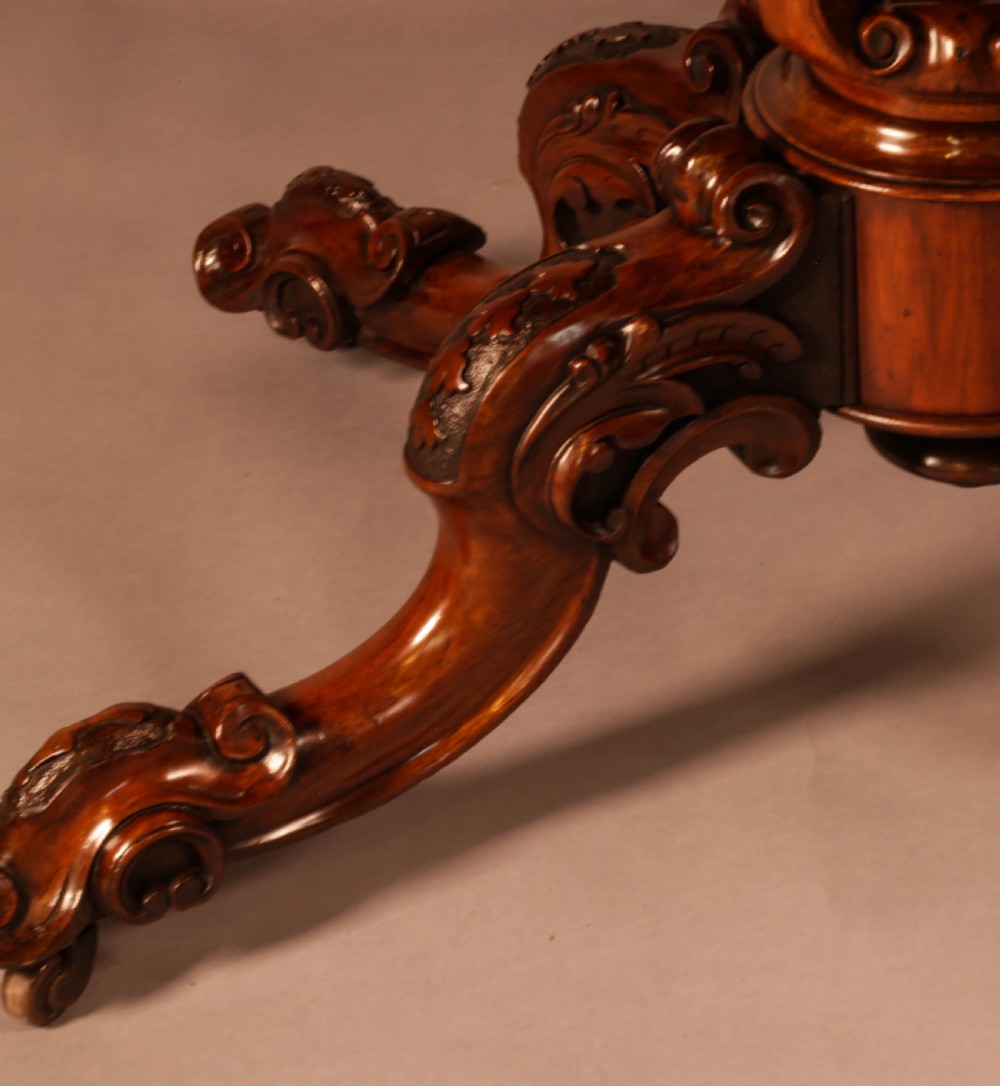 A Victorian burr walnut breakfast table featuring a shaped serpentine top resting on a central carved pedestal column with four scroll-carved legs. View III