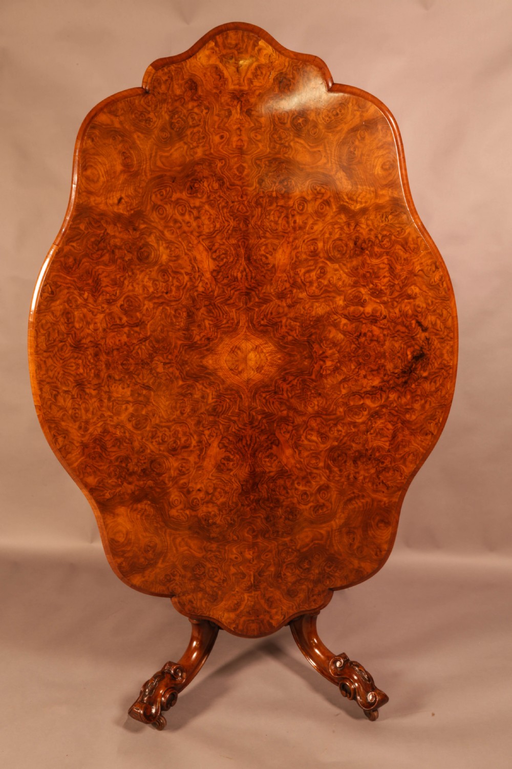 A Victorian burr walnut breakfast table featuring a shaped serpentine top resting on a central carved pedestal column with four scroll-carved legs. View VII