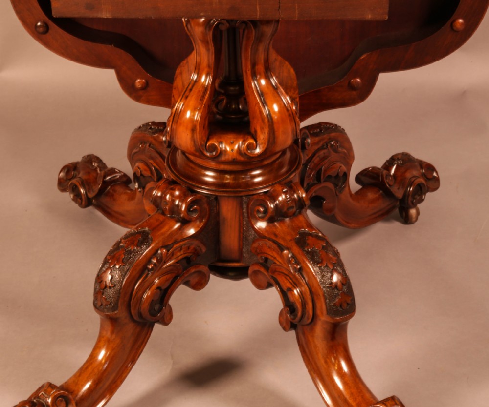 A Victorian burr walnut breakfast table featuring a shaped serpentine top resting on a central carved pedestal column with four scroll-carved legs. View X