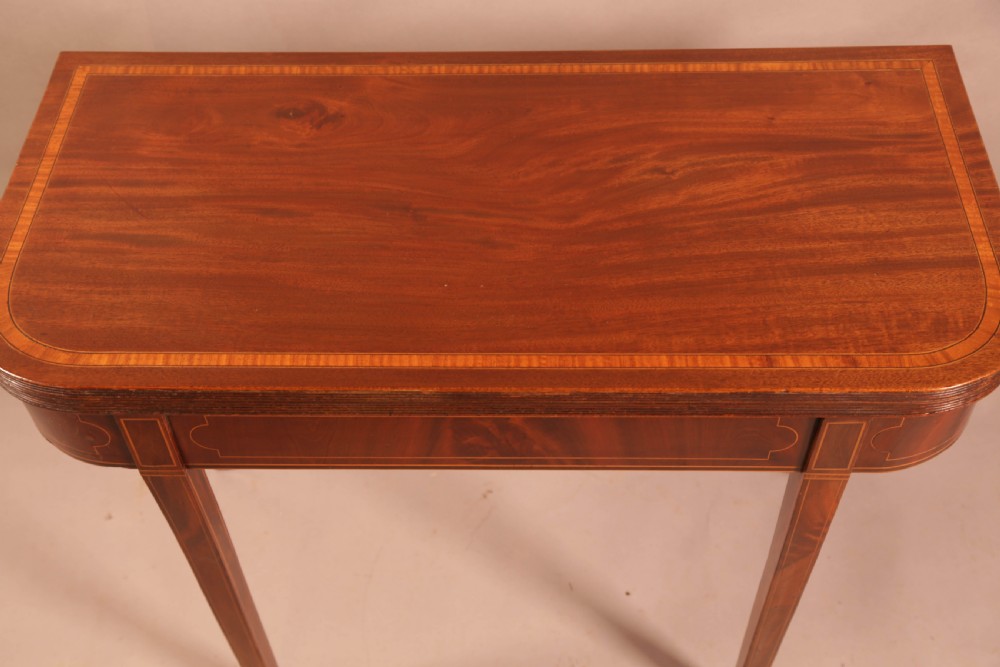 A rectangular Georgian mahogany games table with inlaid banding and tapered legs stands against a neutral background. View IV