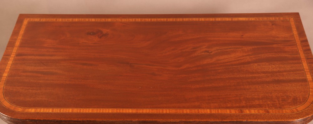 A rectangular Georgian mahogany games table with inlaid banding and tapered legs stands against a neutral background. View VI