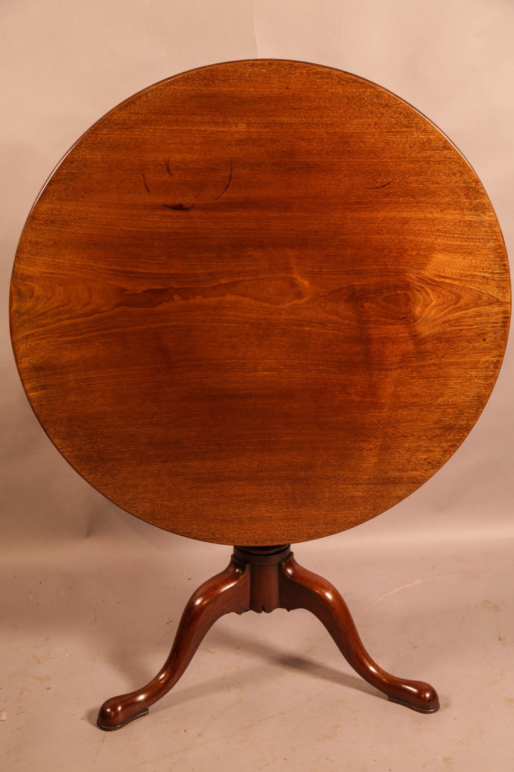A circular mahogany tilt-top supper table supported by a turned central column and three cabriole legs.