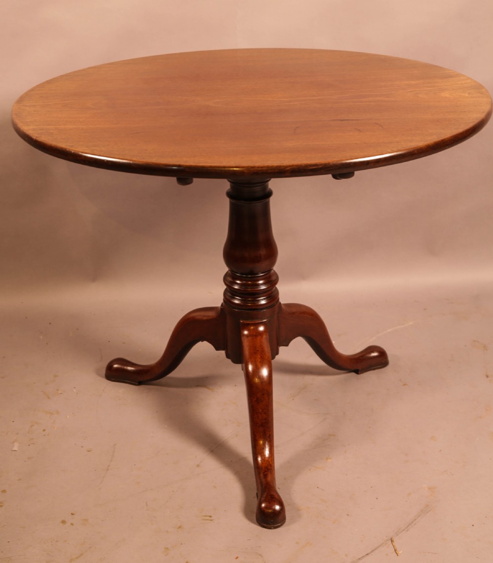 A circular mahogany tilt-top supper table supported by a turned central column and three cabriole legs. View VI