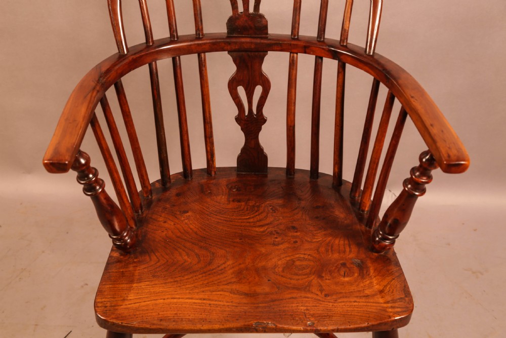 A low-back yew wood Windsor armchair featuring turned legs, a shaped seat, a pierced central back splat, and a curved crinoline stretcher. View V
