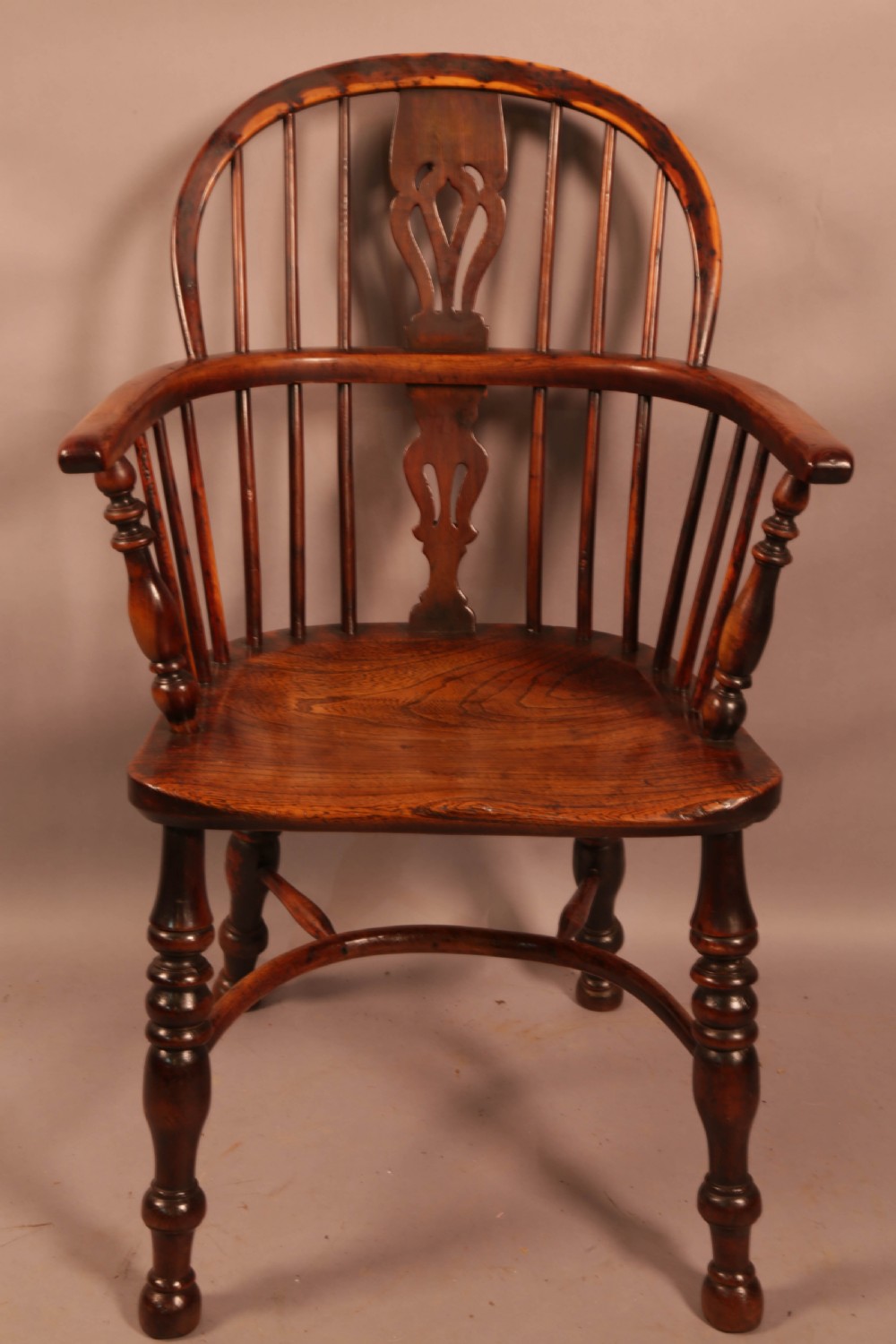 An antique yew wood Windsor armchair with a hoop back, pierced splat, curved armbow, turned legs, and a crinoline stretcher. View II