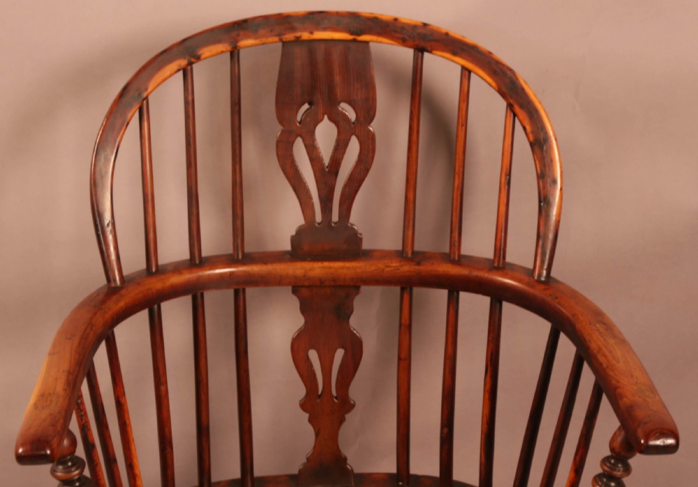 An antique yew wood Windsor armchair with a hoop back, pierced splat, curved armbow, turned legs, and a crinoline stretcher. View V
