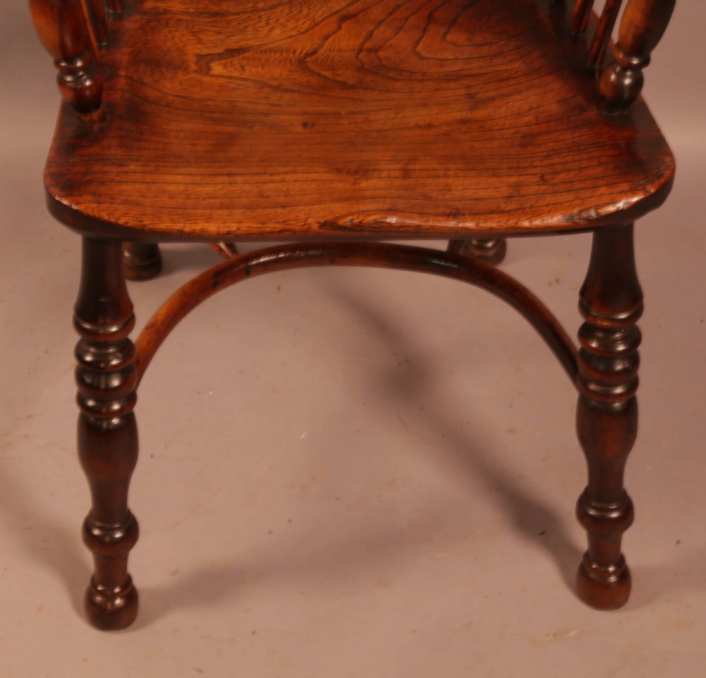 An antique yew wood Windsor armchair with a hoop back, pierced splat, curved armbow, turned legs, and a crinoline stretcher. View VI