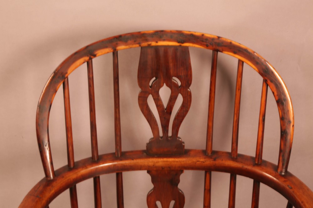 An antique yew wood Windsor armchair with a hoop back, pierced splat, curved armbow, turned legs, and a crinoline stretcher. View VII