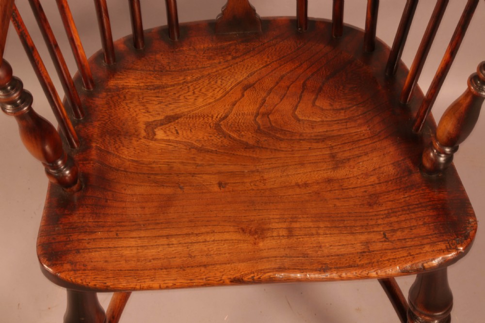 An antique yew wood Windsor armchair with a hoop back, pierced splat, curved armbow, turned legs, and a crinoline stretcher. View X