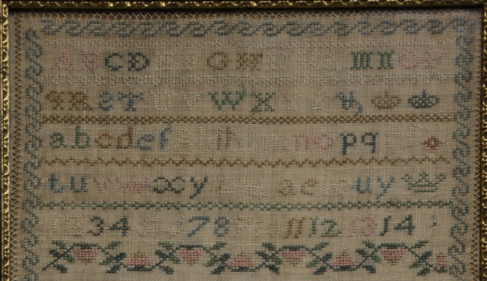 A framed 19th-century needlework sampler on linen featuring embroidered alphabets, numbers, a central verse, floral borders, and a reclining stag motif. View II