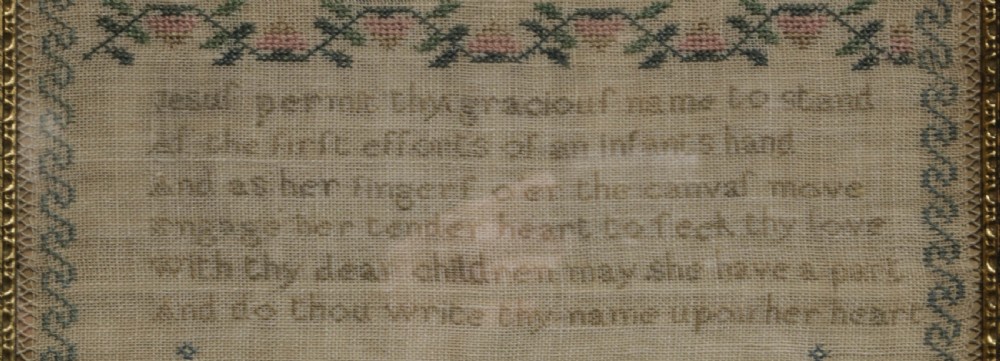 A framed 19th-century needlework sampler on linen featuring embroidered alphabets, numbers, a central verse, floral borders, and a reclining stag motif. View III