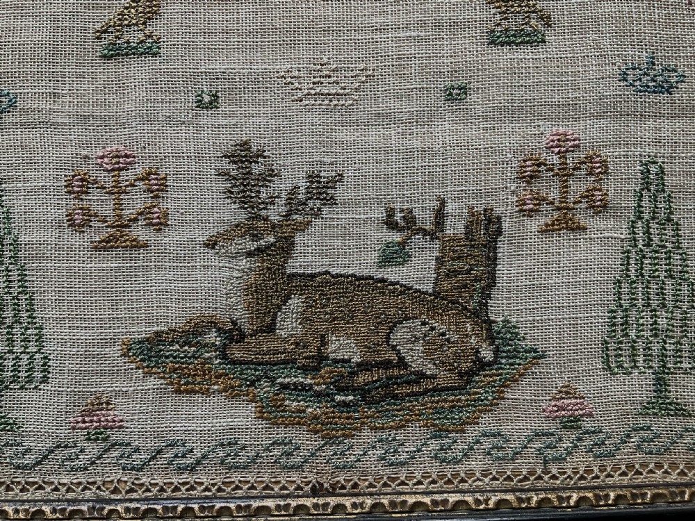 A framed 19th-century needlework sampler on linen featuring embroidered alphabets, numbers, a central verse, floral borders, and a reclining stag motif. View VIII
