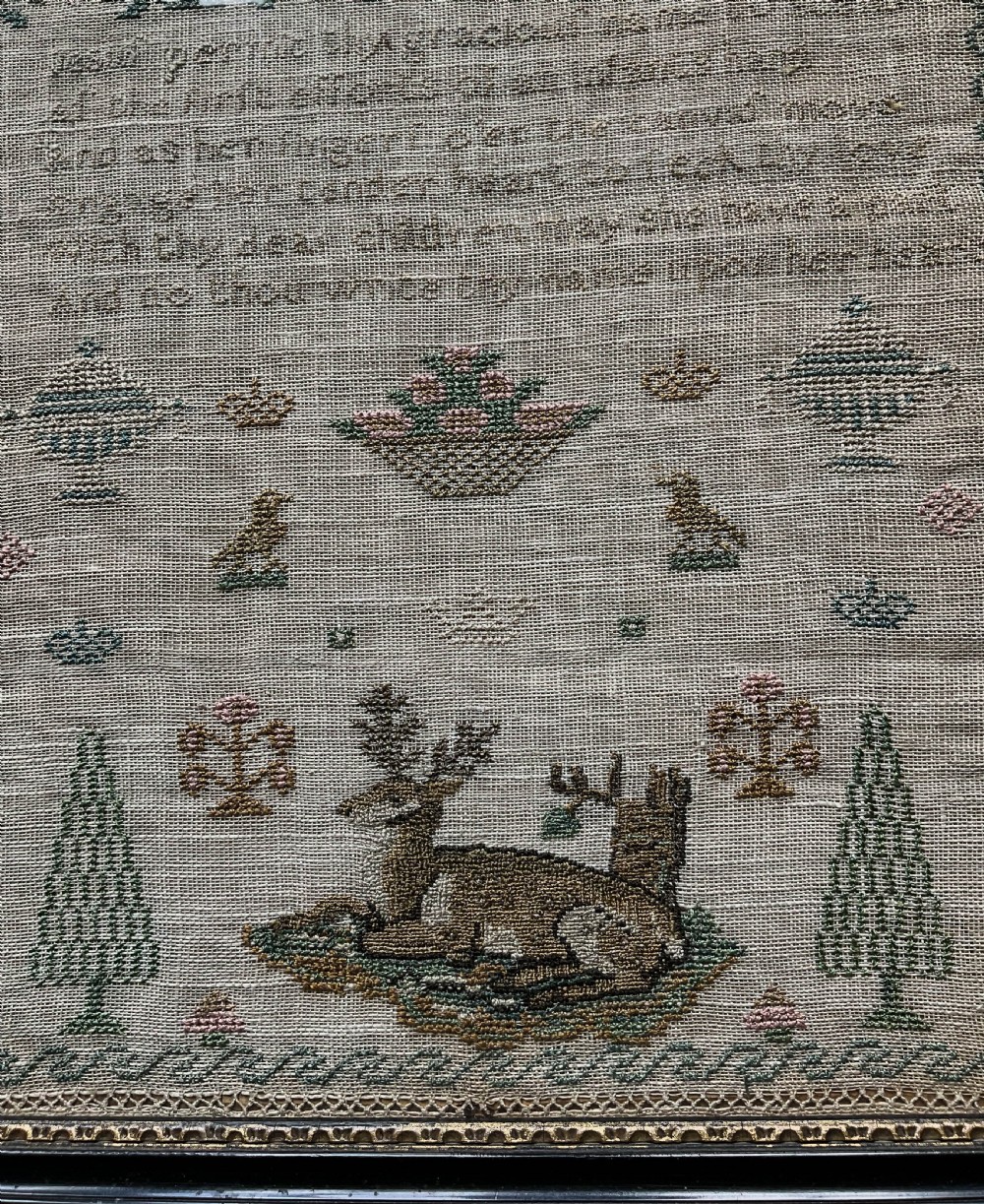 A framed 19th-century needlework sampler on linen featuring embroidered alphabets, numbers, a central verse, floral borders, and a reclining stag motif. View IX
