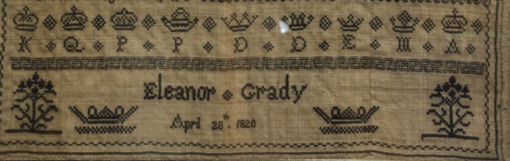 A framed 1820 Georgian needlework sampler featuring embroidered alphabets, numbers, crowns, and a central verse titled On Education on a linen ground. View III