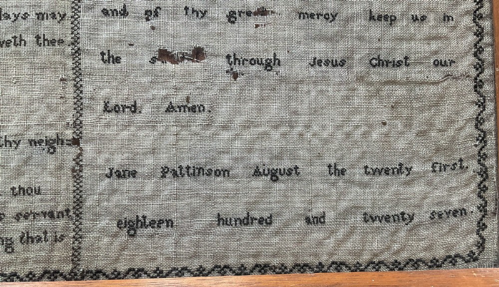An 1827 Georgian embroidered needlework sampler featuring the Ten Commandments, the Lords Prayer, and an alphabet border set in a wooden frame. View III