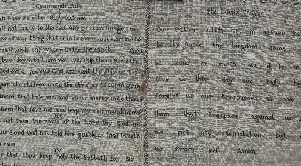 An 1827 Georgian embroidered needlework sampler featuring the Ten Commandments, the Lords Prayer, and an alphabet border set in a wooden frame. View IV