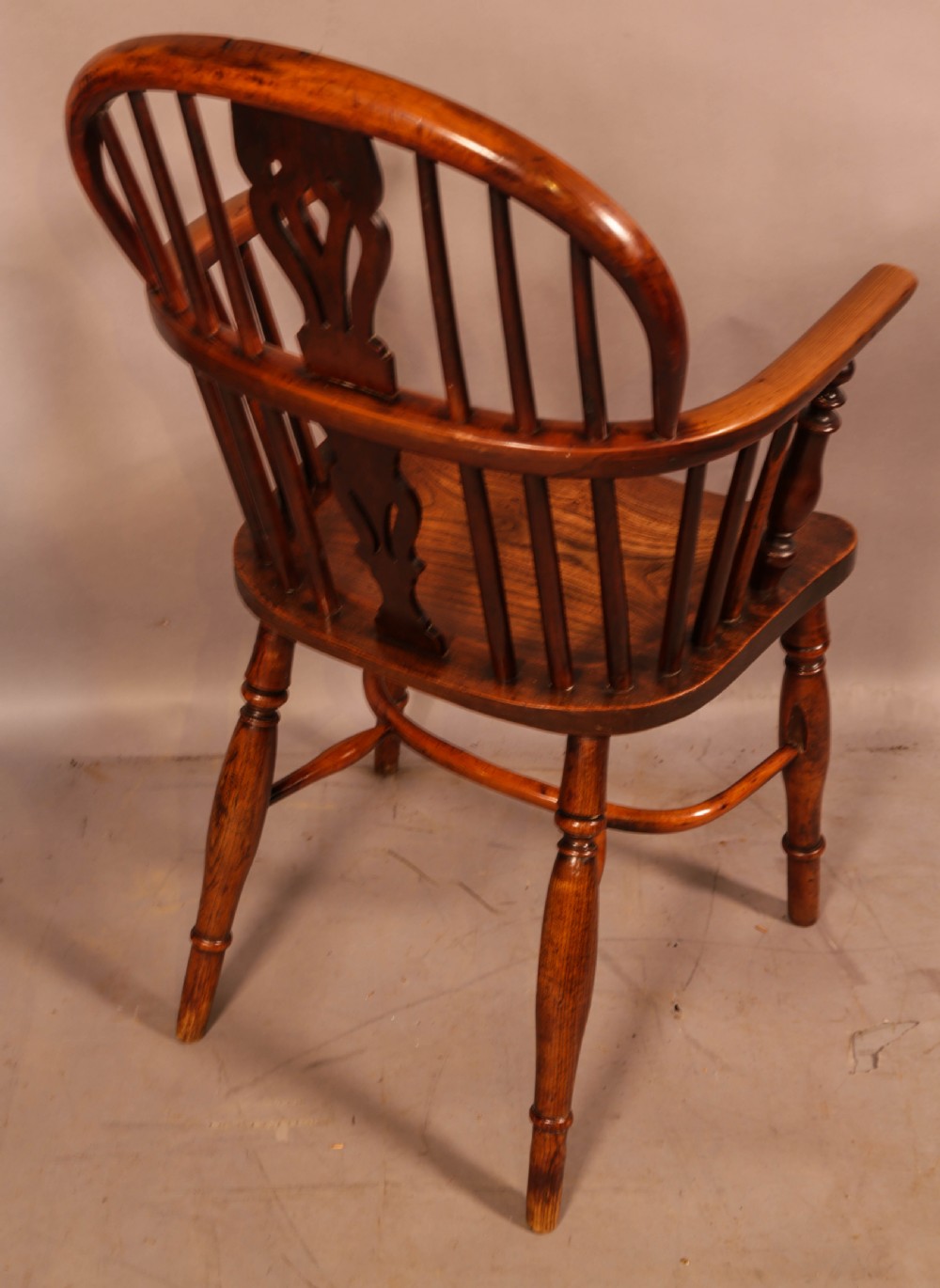 An antique yew wood low back Windsor armchair featuring a pierced central splat, steam-bent arm rail, turned legs, and a crinoline stretcher. View III