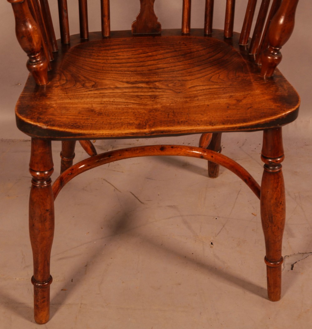 An antique yew wood low back Windsor armchair featuring a pierced central splat, steam-bent arm rail, turned legs, and a crinoline stretcher. View IV