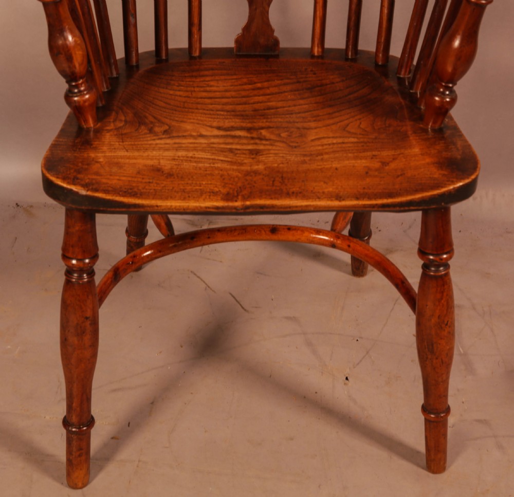 An antique yew wood low back Windsor armchair featuring a pierced central splat, steam-bent arm rail, turned legs, and a crinoline stretcher. View V