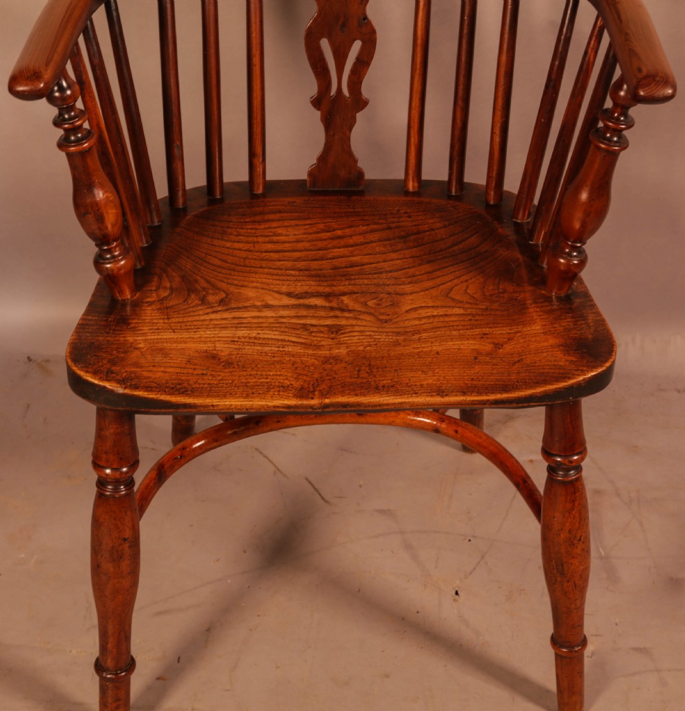 An antique yew wood low back Windsor armchair featuring a pierced central splat, steam-bent arm rail, turned legs, and a crinoline stretcher. View VI