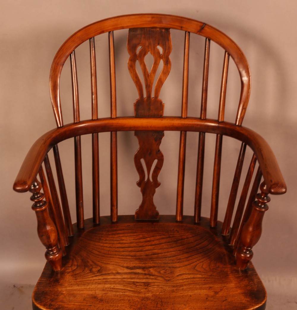 An antique yew wood low back Windsor armchair featuring a pierced central splat, steam-bent arm rail, turned legs, and a crinoline stretcher. View VII
