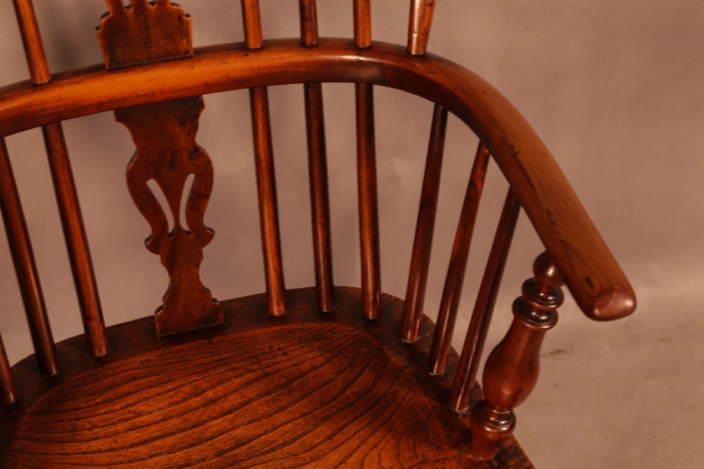 An antique yew wood low back Windsor armchair featuring a pierced central splat, steam-bent arm rail, turned legs, and a crinoline stretcher. View X