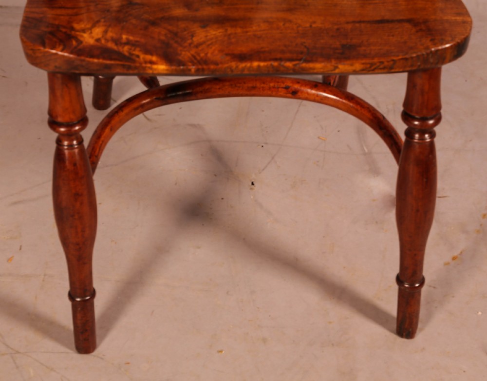 A low back yew wood Windsor armchair featuring turned spindles, a central pierced splat, a shaped seat, and a curved crinoline stretcher. View III