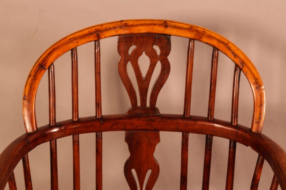 A low back yew wood Windsor armchair featuring turned spindles, a central pierced splat, a shaped seat, and a curved crinoline stretcher. View V