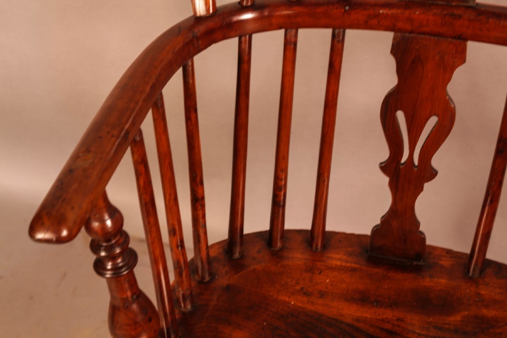 A low back yew wood Windsor armchair featuring turned spindles, a central pierced splat, a shaped seat, and a curved crinoline stretcher. View VI