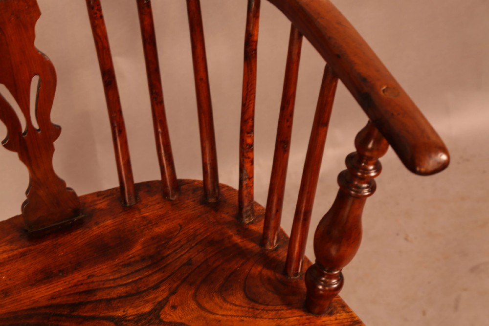 A low back yew wood Windsor armchair featuring turned spindles, a central pierced splat, a shaped seat, and a curved crinoline stretcher. View VII