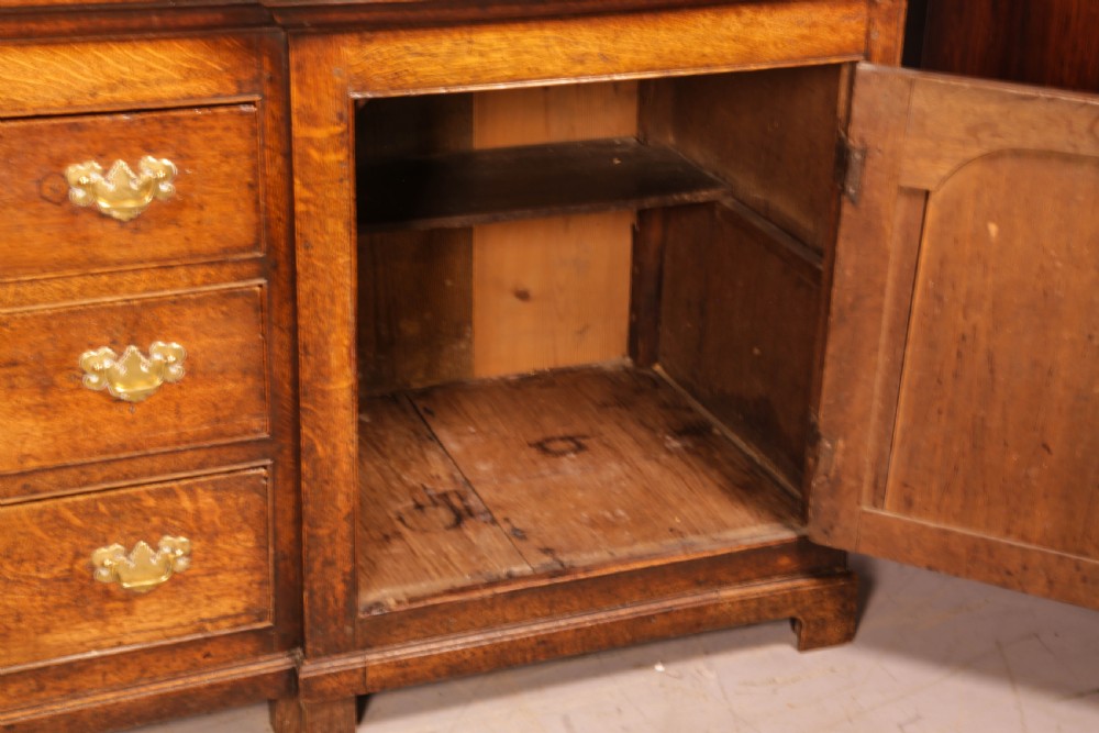 A large antique Georgian oak serving dresser featuring central drawers flanked by panelled cupboards and a stepped top shelf with small drawers. View IV