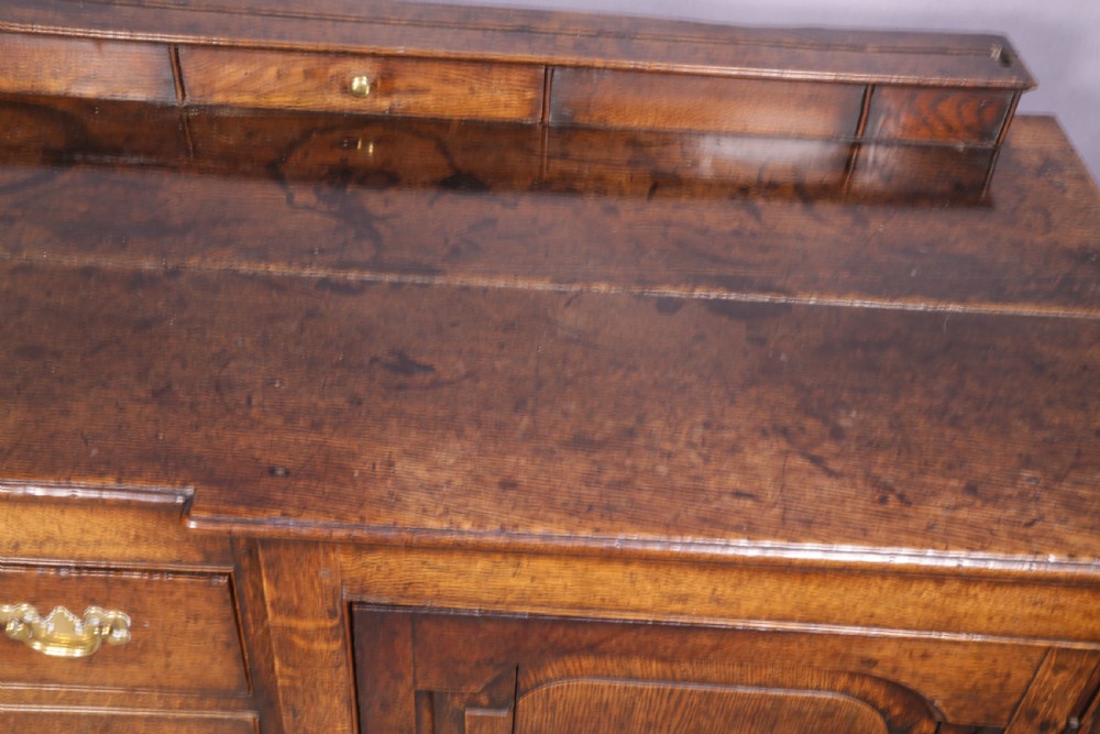 A large antique Georgian oak serving dresser featuring central drawers flanked by panelled cupboards and a stepped top shelf with small drawers. View VIII