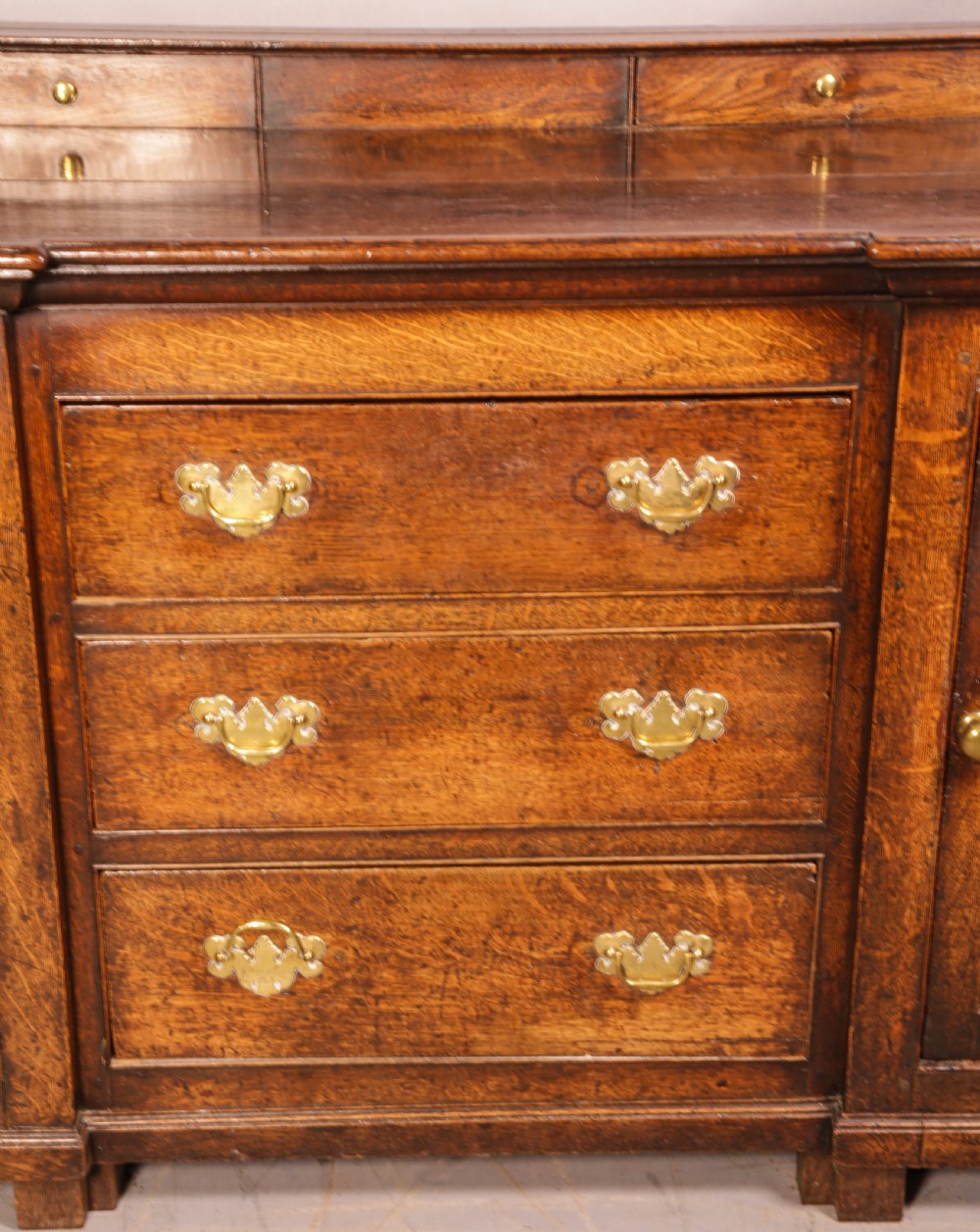 A large antique Georgian oak serving dresser featuring central drawers flanked by panelled cupboards and a stepped top shelf with small drawers. View X