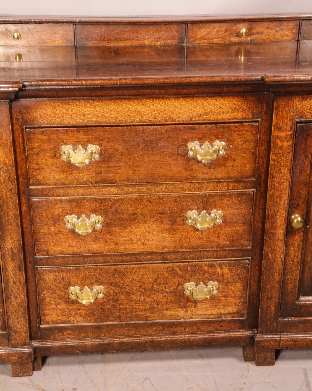 A large antique Georgian oak serving dresser featuring central drawers flanked by panelled cupboards and a stepped top shelf with small drawers. View XI