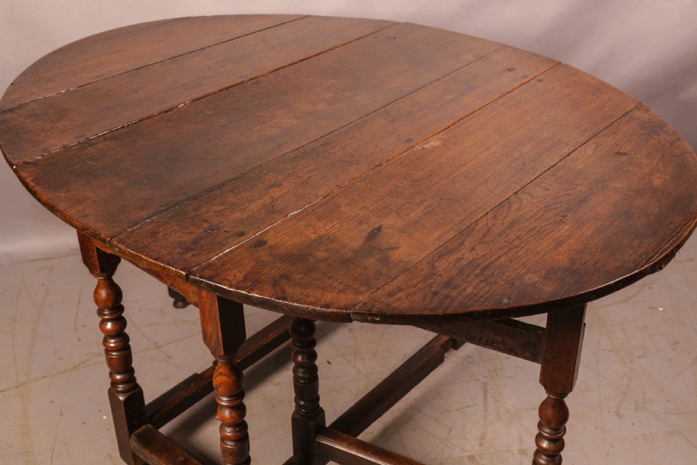 A seventeenth-century oak gateleg dining table featuring two drop leaves, turned legs, perimeter stretchers, and an open end drawer. View IV