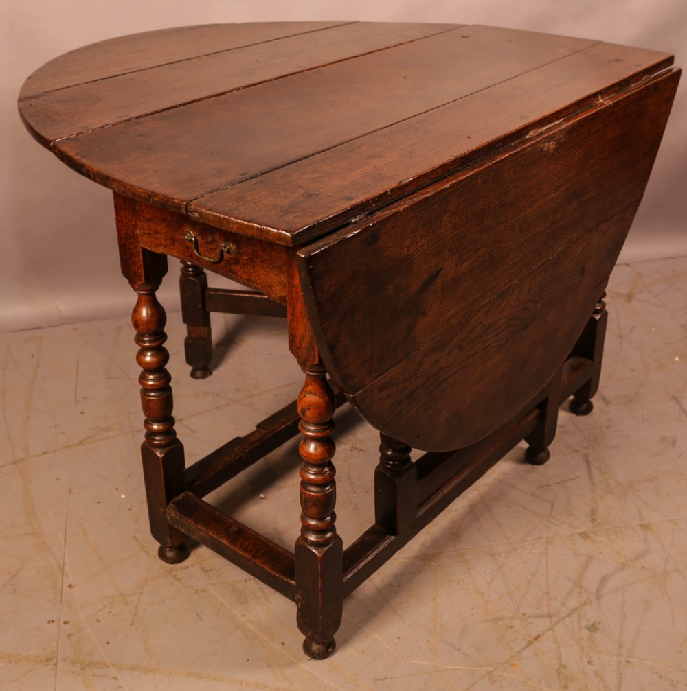A seventeenth-century oak gateleg dining table featuring two drop leaves, turned legs, perimeter stretchers, and an open end drawer. View VIII
