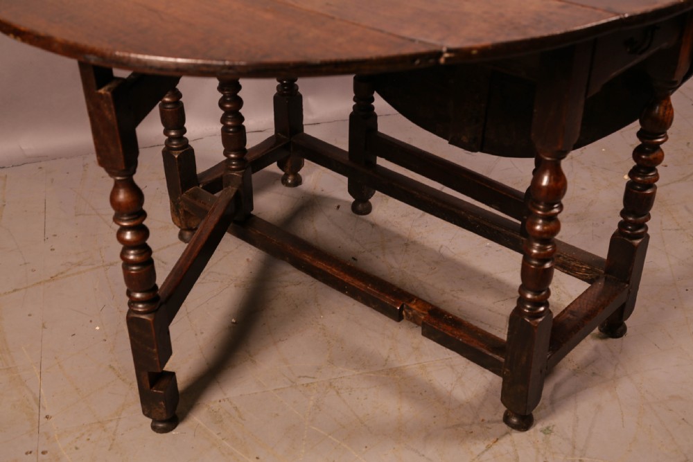 A seventeenth-century oak gateleg dining table featuring two drop leaves, turned legs, perimeter stretchers, and an open end drawer. View IX