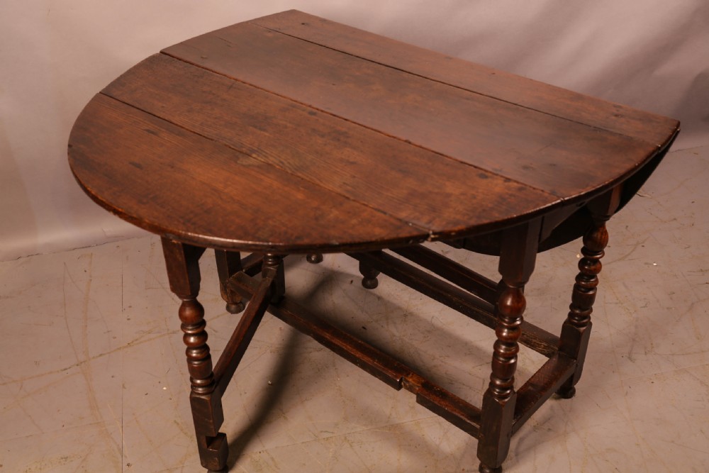 A seventeenth-century oak gateleg dining table featuring two drop leaves, turned legs, perimeter stretchers, and an open end drawer. View X