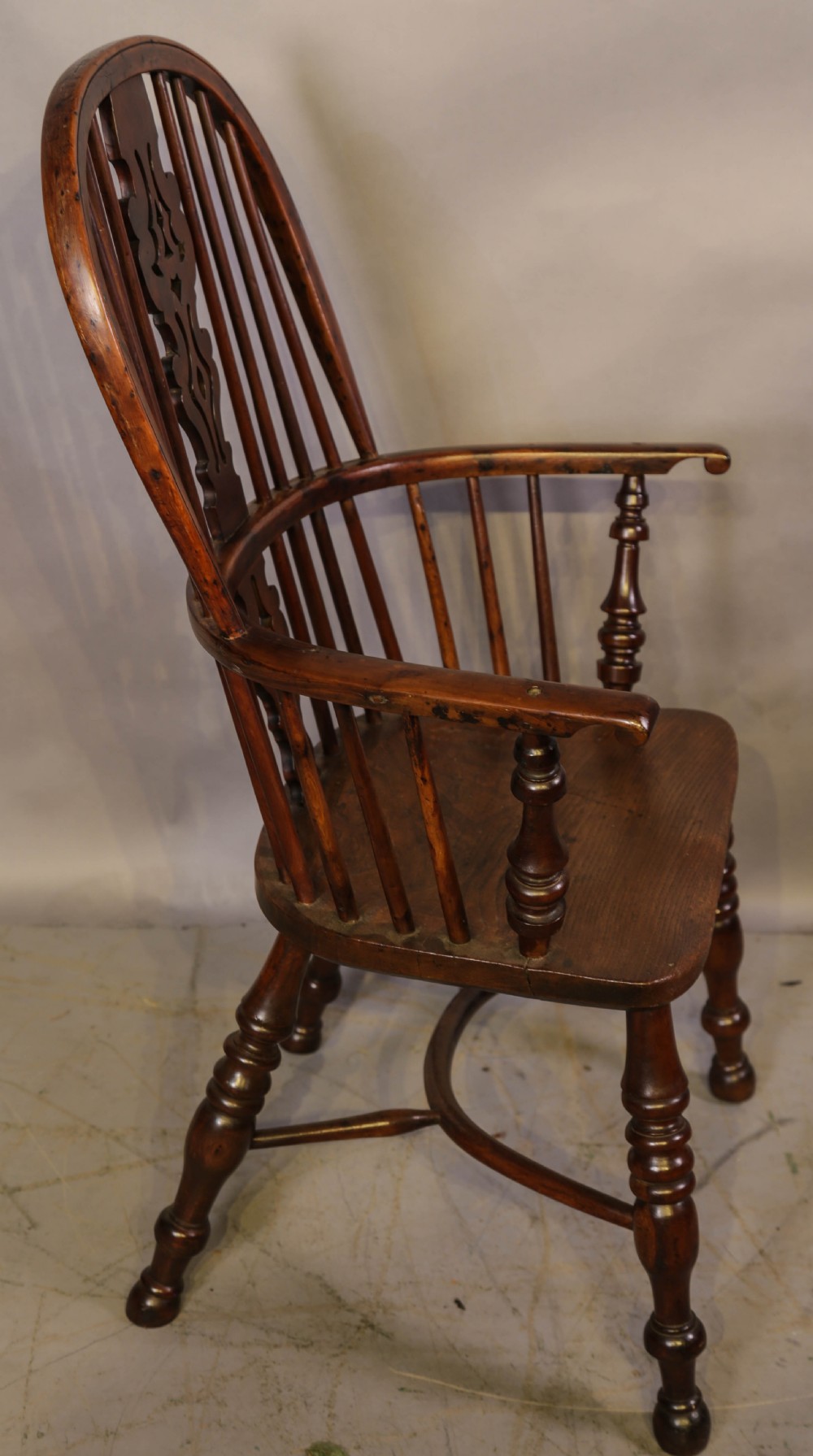 A high-back wooden Windsor armchair featuring a bentwood hoop, pierced central splat, turned spindles, sculpted seat, and baluster legs connected by a stretcher. View II