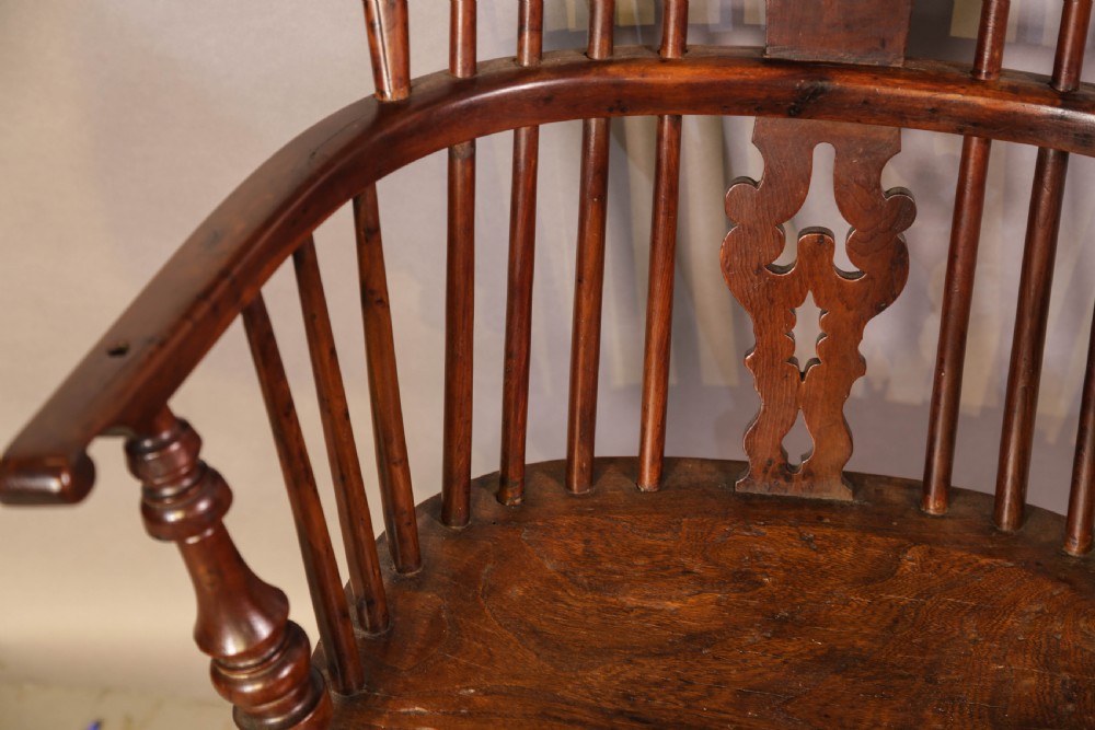 A high-back wooden Windsor armchair featuring a bentwood hoop, pierced central splat, turned spindles, sculpted seat, and baluster legs connected by a stretcher. View VII