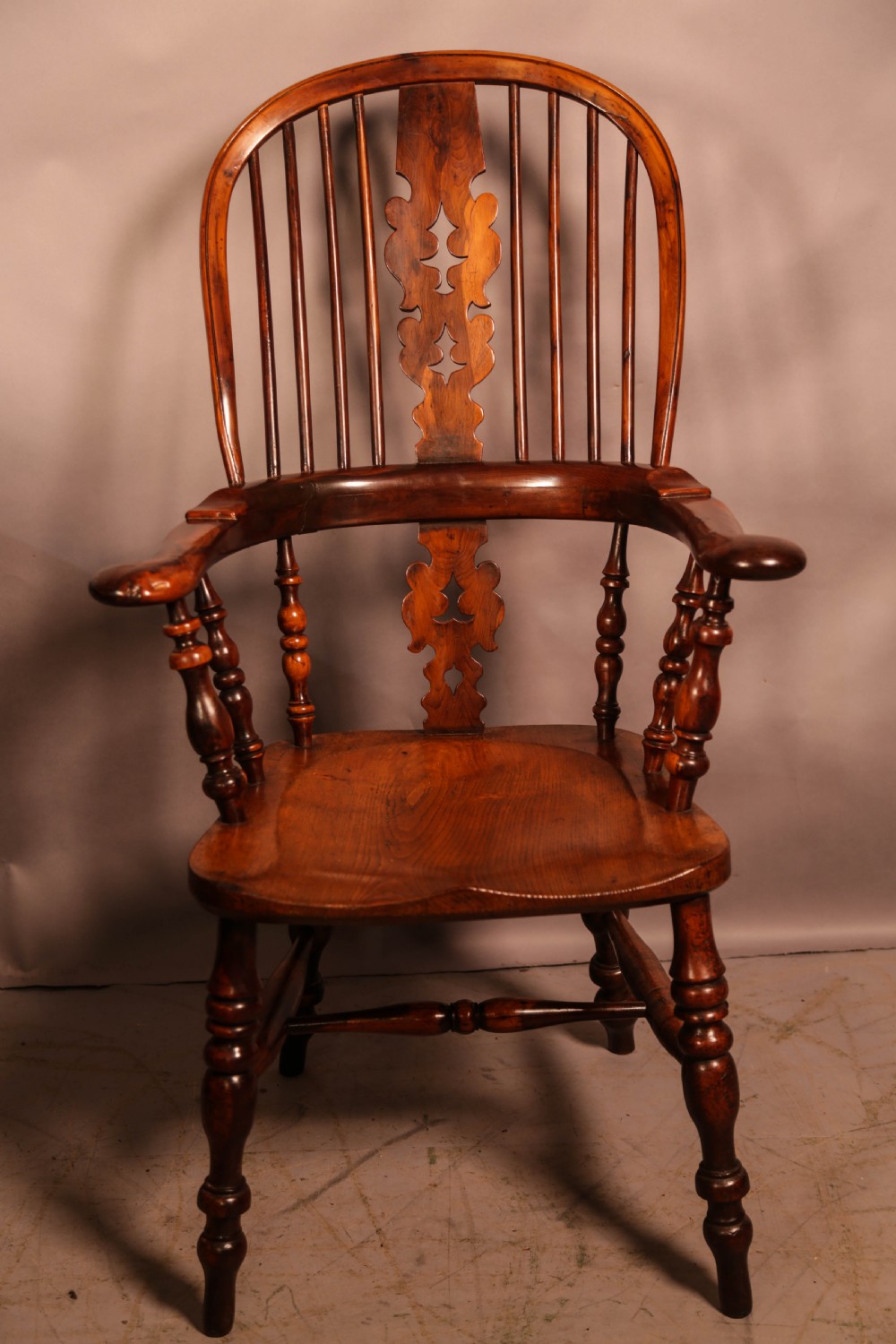 A 19th-century yew wood Windsor armchair featuring a curved hoop back, central pierced splat, turned spindles, broad armrests, and turned legs. View II