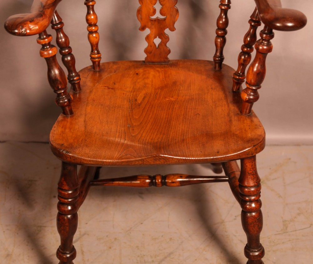 A 19th-century yew wood Windsor armchair featuring a curved hoop back, central pierced splat, turned spindles, broad armrests, and turned legs. View III