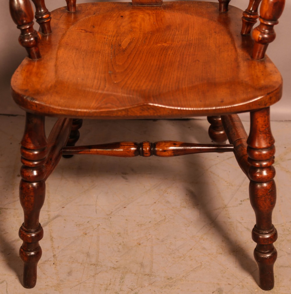 A 19th-century yew wood Windsor armchair featuring a curved hoop back, central pierced splat, turned spindles, broad armrests, and turned legs. View IV
