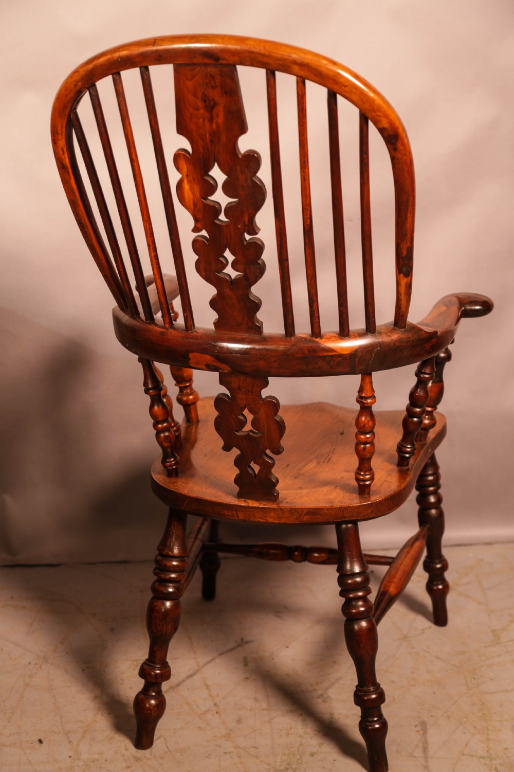 A 19th-century yew wood Windsor armchair featuring a curved hoop back, central pierced splat, turned spindles, broad armrests, and turned legs. View V