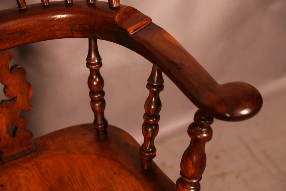A 19th-century yew wood Windsor armchair featuring a curved hoop back, central pierced splat, turned spindles, broad armrests, and turned legs. View IX