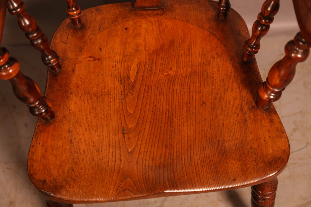A 19th-century yew wood Windsor armchair featuring a curved hoop back, central pierced splat, turned spindles, broad armrests, and turned legs. View X