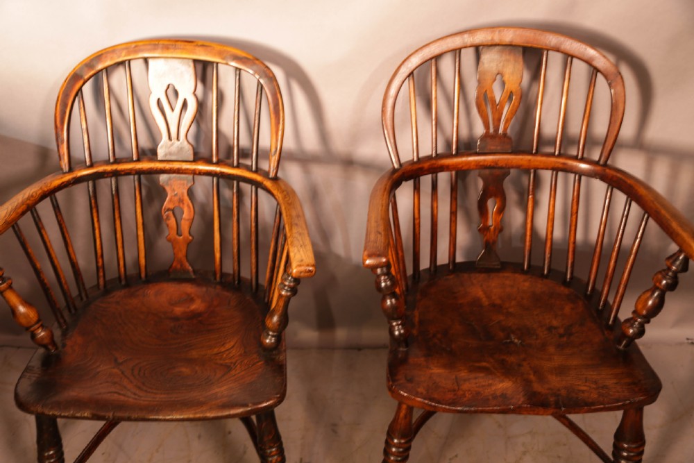 Two antique wooden armchairs featuring curved backrests, central pierced splats, spindle supports, and solid saddle seats. View III