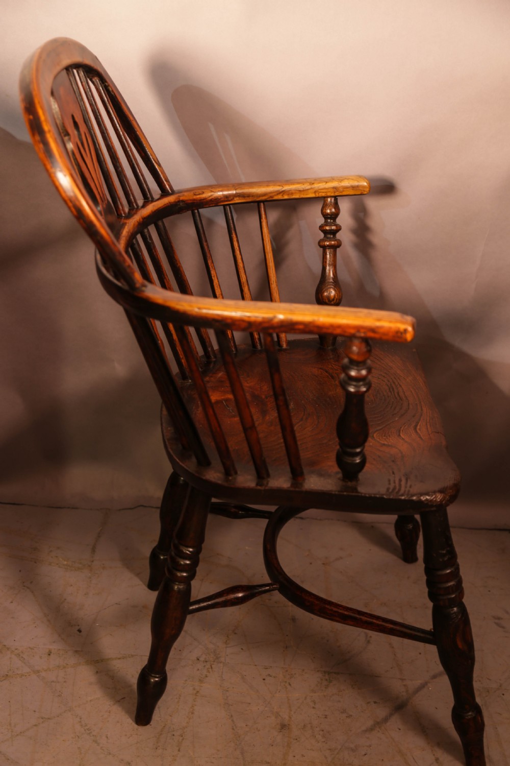 Two antique wooden armchairs featuring curved backrests, central pierced splats, spindle supports, and solid saddle seats. View VI