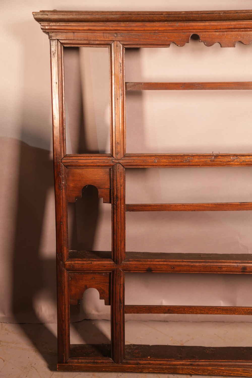 A Georgian dark oak plate rack featuring a scalloped top frieze, horizontal retaining bars, and side alcoves with shaped arch cutouts. View V