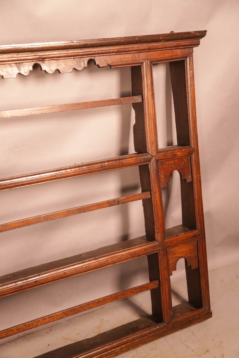 A Georgian dark oak plate rack featuring a scalloped top frieze, horizontal retaining bars, and side alcoves with shaped arch cutouts. View VI